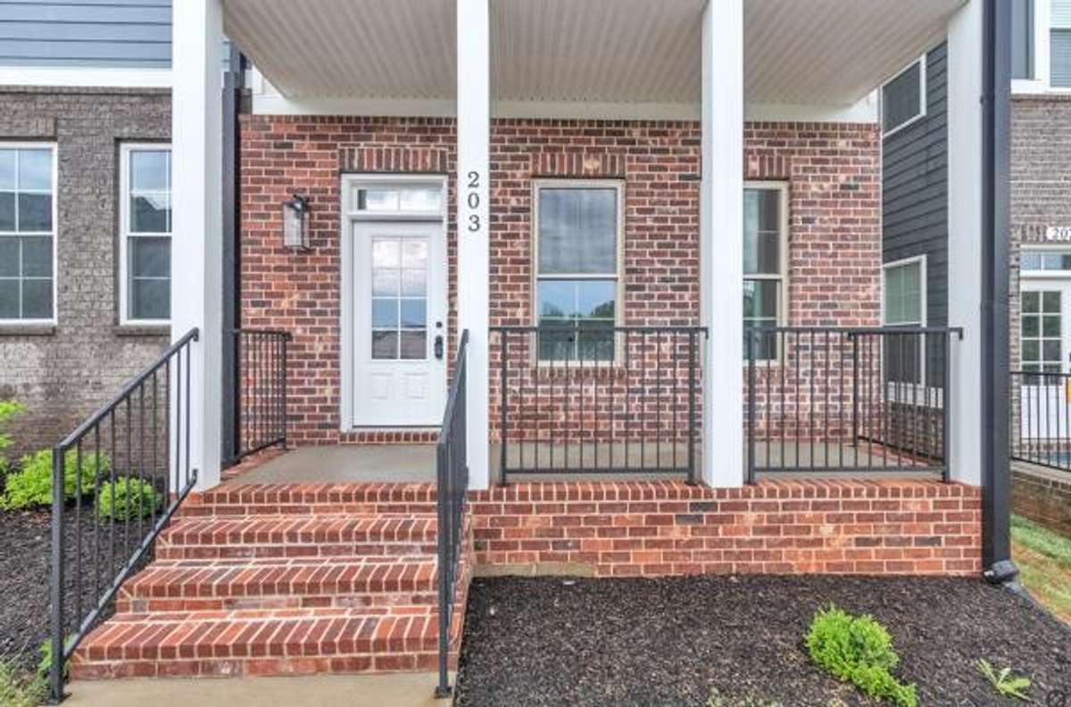 This adorable covered brick front porch is ready for your seasonal plants and decor!