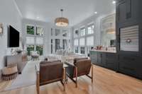 Sunroom with two walls of windows feature a Sub Zero wine refrigerator with two refrigerator drawers, bar with copper sink, special drawers to hold bottles and glazed mirror.