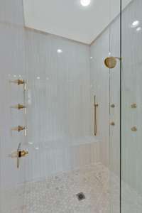 Great glass front shower features 4 body sprays, rain shower head, hand held sprayer and large bench