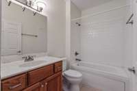 Guest/hall bath with jacuzzi style tub/shower.  Tile flooring in all wet rooms are tile.