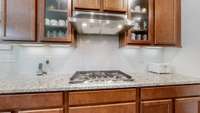 Upgraded kitchen featuring a gas stove with vented hood, built-in microwave and oven, large pantry, and an graded island perfect for meal prep and entertaining.