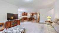Open living room with plenty of windows and wooded views, flowing seamlessly into the kitchen.