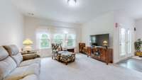 Open living room with plenty of windows and wooded views, flowing seamlessly into the kitchen.