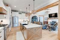 The large island houses a unique black farmhouse-style sink and elegant faucet.  Even the ends of the island are adorned!  The open plan is perfect for entertaining guests while prepping the meal!