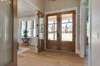 The natural wood accents throughout the home are well-suited for the surroundings.  Multiple sets of glass and wood doors grace the sitting room/office, primary suite, and laundry/drop zone spaces.