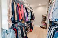 Custom wood built-ins are found throughout the generously-sized primary closet.  You have to turn the corner to see it all...
