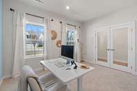 The home office space complete with glass doors is located off the main entry foyer. The space features 2 large windows and an accent wall that matches the front door.