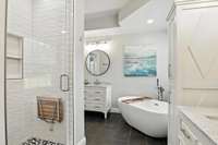The primary bath offers spa-like comfort with furniture-style vanities, a deep soaker tub, ceramic tile flooring, and a beautifully tiled walk-in shower