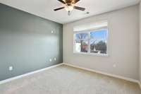 The large bedroom features an accent wall, ceiling fan/light with remote & twin double hung windows with blinds & neutral carpeting.