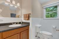 Main Bathroom. Has lovely white tile on walls, and white tile on floors. Scenic view of trees from window.