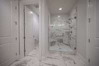 Primary bathroom with marble floors and gorgeous marble/tile shower.