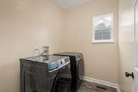 Laundry room tucked away adjacent to kitchen. You will never run out of hot water in this home as there is a tankless water heater located in the attic.