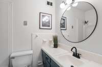The bathroom pairs a modern black faucet with updated lighting for a fresh and refined look.