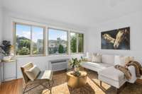 The warm-toned hardwood floors add character and charm, grounding the sun-filled living space with timeless appeal.