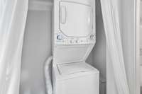 Enjoy the ease of in-unit laundry with a stacked washer and dryer, discreetly tucked behind curtains.