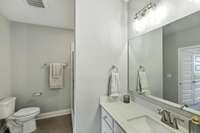 Modern bathroom with quartz countertop and large mirror.