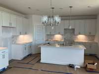 Check out this amazing kitchen!!  Tall White Cabinets, upgraded tile backsplash, Stainless appliances with gas stove, Pendant lights over island that has quartz.