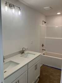 Secondary bathroom with dual sinks, upgraded lighting and tile flooring