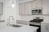 Check out the spacious kitchen with the optional upgraded tall cabinets.  Quartz countertops, tile backsplash, and stainless appliances with gas stove included.  Colors and selections may vary