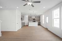 Check out the spacious Great Room looking into the kitchen with the optional upgraded tall cabinets.  Quartz countertops, tile backsplash, and stainless appliances with gas stove included.  Colors and selections may vary