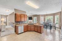 Granite counter tops, wooden cabinets, and a handsome tile floor complete this open kitchen.