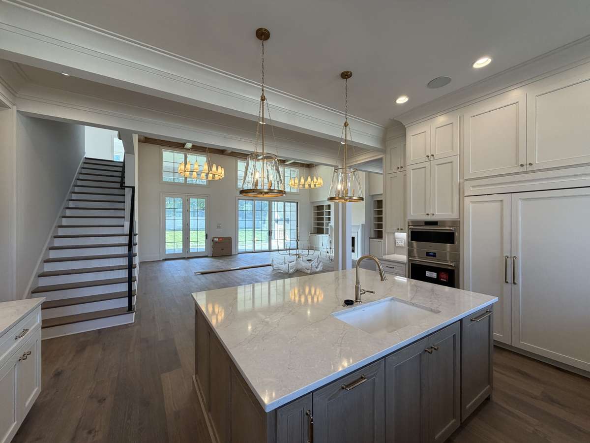 Spacious gourmet Kitchen with Wolf appliances including three ovens, a hidden pantry, quartz countertops, backsplash, and a flush island. 
Photo taken: 3/20/26
