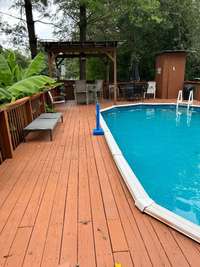 Another view of the pool with large deck, covered sitting area, and plumbed outdoor potty
