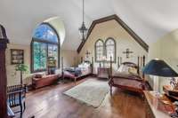 This spacious bedroom feels like a private sanctuary. The towering  arched windows filter soft light into the room and overlooks the pool in the backyard.