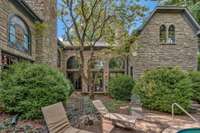 An outdoor fireplace is nestled in the u-shaped courtyard. The redbud in the center of the u-shape blooms its heart out with vibrant purple pinkish flowers each spring that you can see through all the windows on the back of the house.