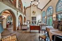 A grand, dramatic fireplace is a centerpiece to the Great room as arched windows and arched openings frame the space. French doors open up to the pool which makes it great for entertaining. The house makes a u-shape on the backyard framing the pool