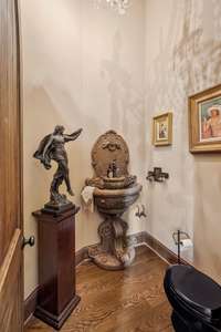 This half bath on the main level is a jewel box of elegance. Though compact the tall ceiling adds vertical grandeur