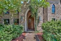 Storybook-romantic, Gothic style grand front door framed by greenery and timeless stonework/ limestone