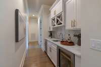Butler’s pantry featuring marble countertops, custom cabinetry, wine storage, and a built-in beverage fridge.