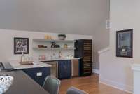 Stylish bar area with open shelving, beverage fridge, and plenty of counter space.