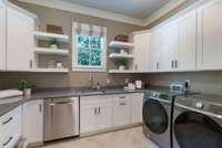Well-appointed laundry room featuring ample cabinetry, built-in sink, and modern appliances for effortless organization and convenience.