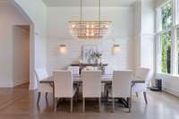 Elegant formal dining room featuring floor-to-ceiling windows with abundant natural light.