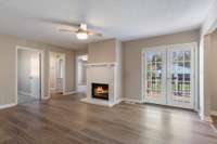 Den with wood buring fireplace, modern lighted ceiling fan and deck access.