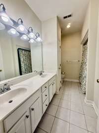 Primary bath with tile flooring; custom white cabinets with marble tops; tub/shower combo; lots of extra storage throughout the home