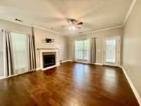Living Room with new hardwood flooring; gas fireplace; Crownmold and ceiling fan overlooking covered patio;
