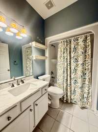 Guest Bath on main level with tile flooring, tub/shower combo with white custom cabinet with marble top; Extra closet storage