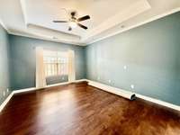Primary Bedroom Suite on main level; new hardwood flooring; Trey ceiling with recessed lighting overlooking covered patio.
