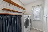 Laundry room with tile flooring, shelving, storage area and washer/dryer to remain.