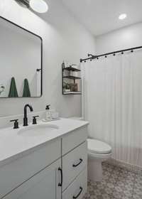 Oversized vanity, decorative tile floor and black fixtures in the hall bath.