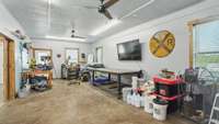 In the outbuilding is a dedicated workshop.  An exterior door leads to the driveway adjacent to the main home.  The rolling barn door to the left opens to an expansive garage and equipment storage area.