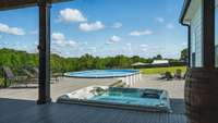 View from the covered porch to the pool area.  Notice the serene view of woods beyond.