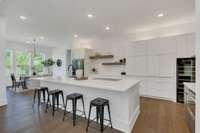 A Modern Minimalist Kitchen with clean lines and uncluttered spaces, featuring, double ovens, a Wolf Induction cooktop, and a wine chiller!