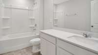 THE GUEST BATHROOM OFFERS A STYLISH QUARTZ-TOPPED VANITY AND TUB/SHOWER COMBO - COMBINING FUNCTION AND COMFORT FOR EVERYDAY USE OR VISITING GUESTS