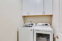 Convenient laundry room with storage cabinets and washer and dryer convey!