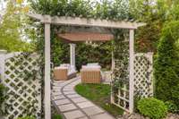 The backyard is like being immersed in your own Secret Garden with mature privacy trees, stone pathways, trellis with climbing white roses, and candlelit chandeliers - all inviting you into the magic of nature