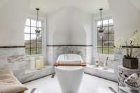 The spa-like bathtub in the primary suite is surrounded by windows and views of the rolling hills